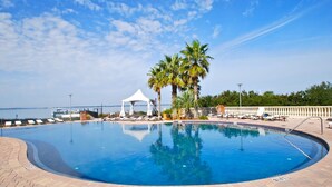 A circular swimming pool with a white canopy and palm trees, surrounded by lounge chairs and a view of the sea. - Sept Special: 7 nights just 1229 plus resort fees.  Great view & location (Pensacola Beach)