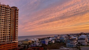 A high-rise hotel with multiple balconies and a view of the beach and ocean at sunset. - Sept Special: 7 nights just 1229 plus resort fees.  Great view & location (Pensacola Beach)