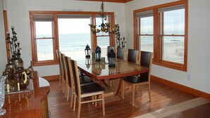 A dining area with a large table, chairs, and a view of the ocean through large windows. - Beautiful beach home on the Jersey Shore (Point Pleasant Beach)
