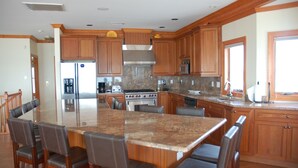 A spacious kitchen with wooden cabinets, a large island with seating, stainless steel appliances, and a granite countertop. - Beautiful beach home on the Jersey Shore (Point Pleasant Beach)