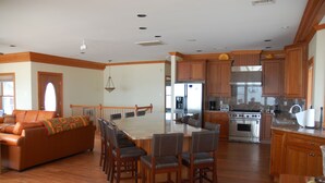 A spacious living area with a large wooden dining table surrounded by chairs, a sofa, and a kitchen with wooden cabinets and stainless steel appliances. - Beautiful beach home on the Jersey Shore (Point Pleasant Beach)