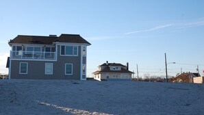 A two-story house with a balcony, a smaller attached house, and a sandy ground. - Beautiful beach home on the Jersey Shore (Point Pleasant Beach)