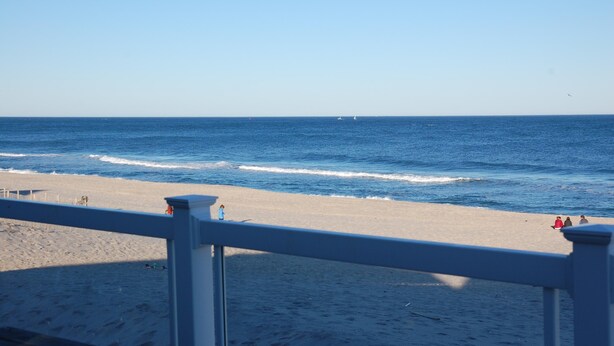 A beach with a wooden deck and a railing, a sandy shore, and the ocean. - Beautiful beach home on the Jersey Shore (Point Pleasant Beach)