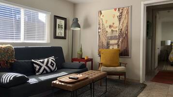 En stue med sofa, sofabord, stol, lampe og et billede.