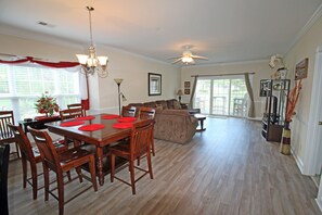 A spacious living room with a dining area, wooden flooring, and a ceiling fan.