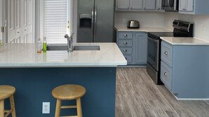 A kitchen with a central island, stainless steel appliances, and blue cabinetry.