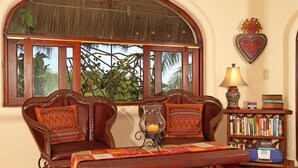 A cozy room with a large window, a wooden bench, a bookshelf, and a decorative heart on the wall.