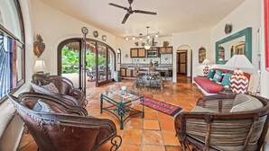 A spacious living area with a dining table, chairs, a sofa, and a ceiling fan.