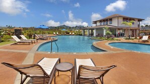 A pool area with lounge chairs and a building in the background. - Pili Mai 11I: Tropical Condo w/ Fairway Views, AC, Shared Pool & Jacuzzi (Koloa)