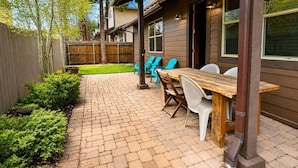 A patio with a wooden table and chairs, a brick pathway, and a wooden fence. - Relax in the Pines at the Flagstaff Base Camp (Flagstaff)