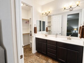 A bathroom with a double sink, dark cabinets, a large mirror, and a light fixture above the mirror. - Relax in the Pines at the Flagstaff Base Camp (Flagstaff)