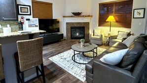 A modern living room with a fireplace, a television, a sofa, and a dining area. - Relax in the Pines at the Flagstaff Base Camp (Flagstaff)