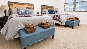 A bedroom with two beds, a blue bench, and a window with blinds. - Relax in the Pines at the Flagstaff Base Camp (Flagstaff)