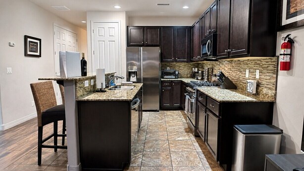 A modern kitchen with dark cabinetry, stainless steel appliances, and a central island. - Relax in the Pines at the Flagstaff Base Camp (Flagstaff)