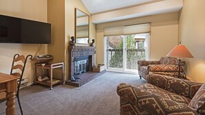 A living room with a fireplace, a television mounted on the wall, a sofa, and a lamp.