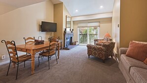 A dining area with a wooden table and chairs, a television mounted on the wall, and a fireplace.