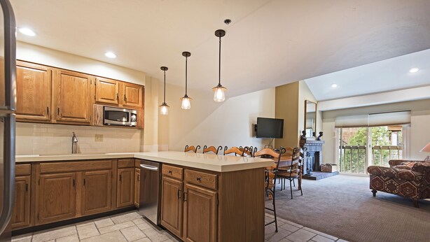 A spacious kitchen with wooden cabinets, a central island, and pendant lighting.