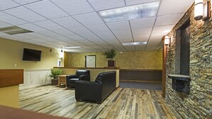 A lobby with a wooden floor, seating area, a television, and a stone wall.