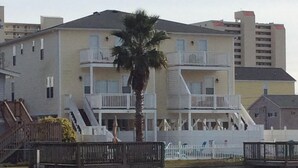 Ein mehrstöckiges Gebäude mit Balkonen, einer Palme und Blick auf das Wasser.