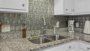 Una cocina con encimeras de granito, fregaderos de acero inoxidable y azulejos decorativos en la pared.