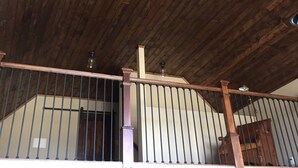 Techo de madera con ventilador y escalera con barandilla.