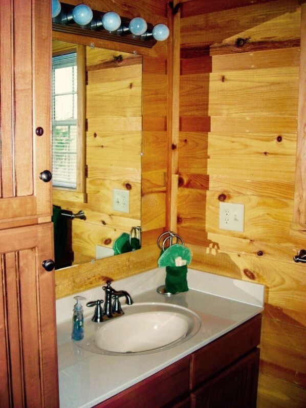 A wooden cabin-style bathroom with a white sink, a mirror, and a green soap dispenser. - 9 Secluded Acres, Hot Tub & Pet Friendly. Close to Restaurants & River Rafting (Ocoee)