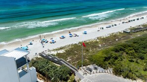 A beach with a wooden boardwalk, beach umbrellas, and a flag. - Upscale Home with Breathtaking Gulf Views Steps to Beach + Pool w/7 Beach Bikes! (Inlet Beach)