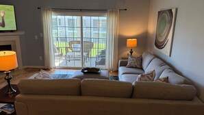Ein Wohnzimmer mit einer Couch, einem Fernseher, einer Lampe und Blick ins Freie.