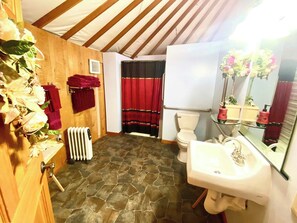 A bathroom with a stone floor, white sink, and red towels.