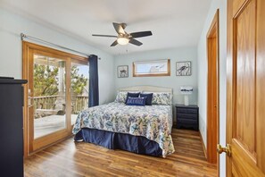 A bedroom with a bed, a ceiling fan, a nightstand, and a window.