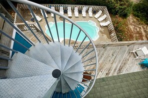 A spiral staircase leading to a pool area with lounge chairs.