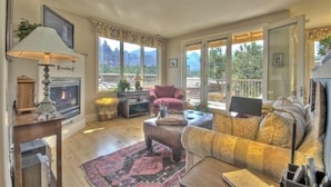 A spacious living room with a fireplace, comfortable seating, and large windows offering a mountain view. - Million Dollar Views! Walk to Restaurants, Shops, Trails. Hot tub, Lounges, Deck (Sedona)