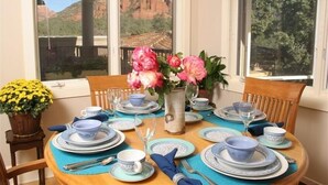 A dining table set with blue and white plates, glasses, and a vase with pink flowers. - Million Dollar Views! Walk to Restaurants, Shops, Trails. Hot tub, Lounges, Deck (Sedona)