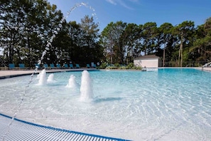 Relax by the tranquil pool surrounded by lush greenery and lounge chairs.