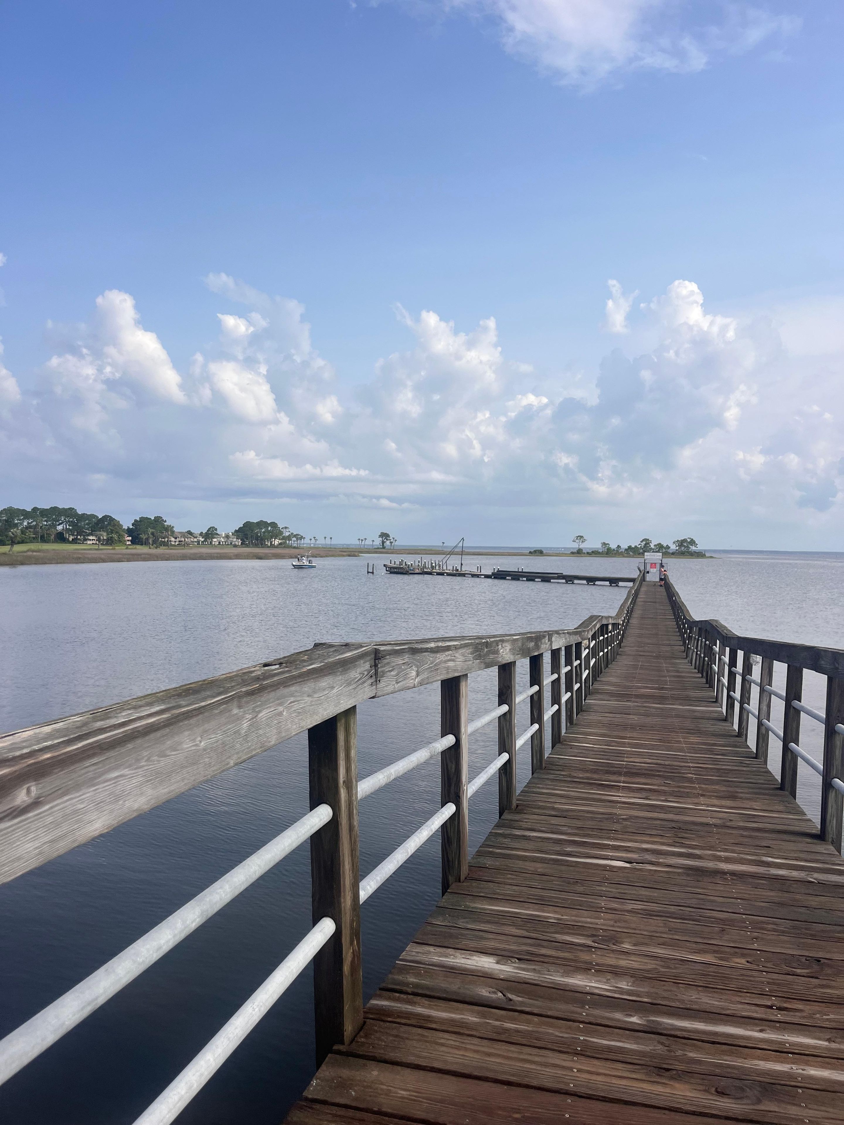 A wooden pier extending into calm water with a clear sky above.