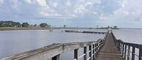 A wooden pier extending into calm water with a clear sky above.