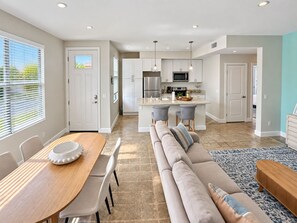 A modern kitchen with white cabinets, stainless steel appliances, and pendant lighting.