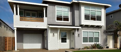 A two-story house with a garage, a balcony, and a well-maintained lawn.