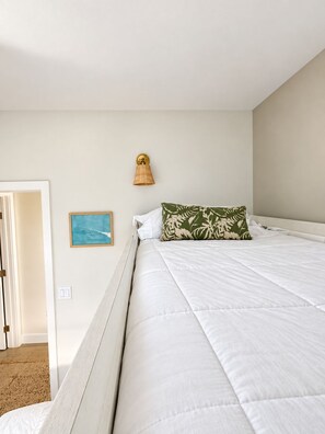 A bedroom with a bed, a wall-mounted lamp, and a framed picture.