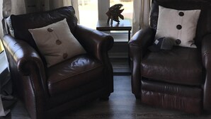 A room with two leather armchairs, a small table, a lamp, and a view through a window with curtains. - Updated, spacious Gulf-front Condo- just steps to the beach! (Panama City Beach)