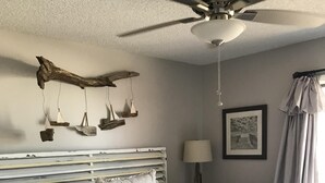 A bedroom with a bed, a ceiling fan, a framed picture, and a window with curtains. - Updated, spacious Gulf-front Condo- just steps to the beach! (Panama City Beach)