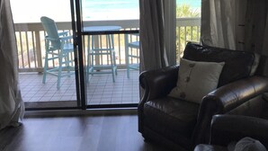 A living room with a sliding glass door leading to a balcony overlooking the ocean. - Updated, spacious Gulf-front Condo- just steps to the beach! (Panama City Beach)