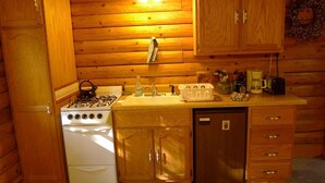 Eine kleine Küche mit Holzausstattung, einem Herd, einem Spülbecken und einem Kühlschrank.