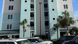 Un hotel su più piani con un atrio centrale, balconi su ogni piano e un’area parcheggio antistante.