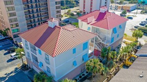 A multi-story hotel with a red roof, balconies, and a parking lot. - Condo pool garage short walk to beach (Myrtle Beach)