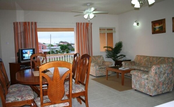A living room with a dining table, chairs, a sofa, a TV, and a ceiling fan.