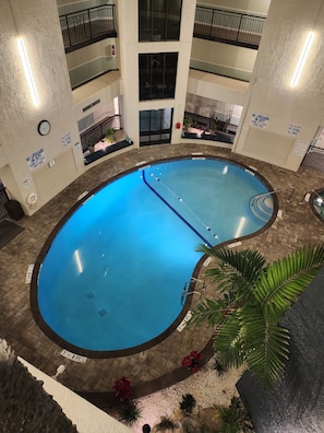 Una piscina interior con varios niveles de balcones, señalización de seguridad y suelo de baldosas.