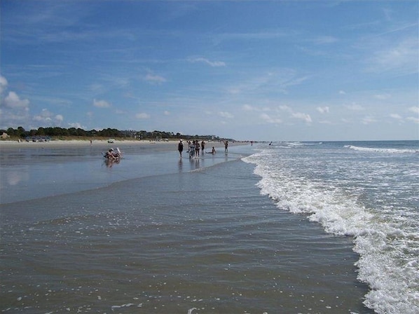 Una playa con gente caminando por la orilla.