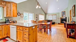 A spacious kitchen with wooden cabinets, a central island, and a dining area with chairs. - Sequoias East (Yosemite National Park)