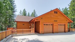 A wooden cabin with a garage, surrounded by trees. - Sequoias East (Yosemite National Park)